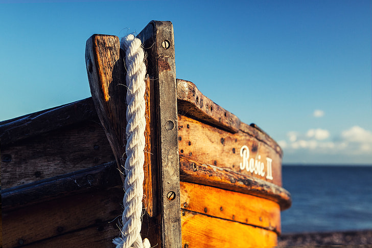 Royalty-Free photo: A wooden fishing boat rests on the beach on a sunny day  in Deal in Kent, England