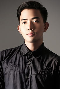 man standing near wall wearing black button-up collared shirt