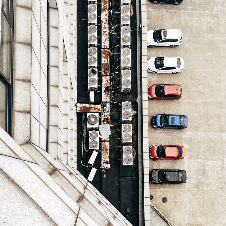 seven cars parked in front of white building top view photography during daytime
