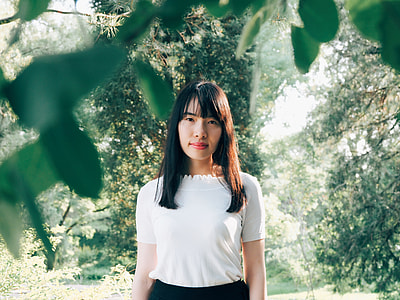 black haired woman in white shirt surround by green trees during daytime
