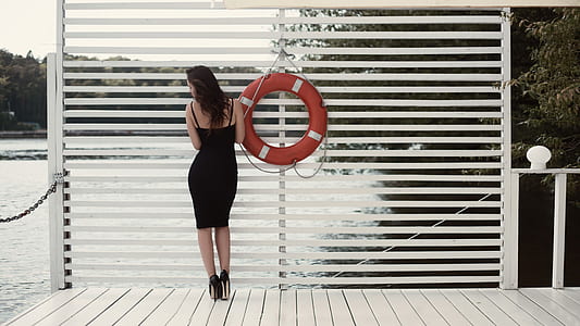 Woman in Black Sheath Dress Beside Swim Ring on Dock