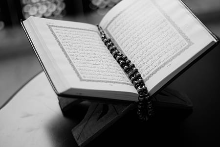 grayscale photography of white book with tesbih prayer beads bookmark on top