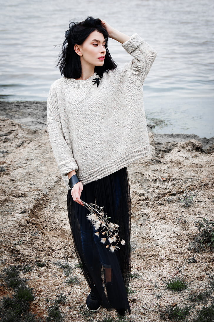 woman in gray sweater holding white flowers