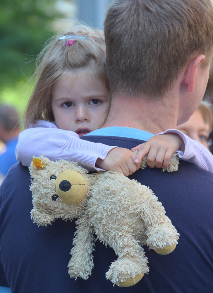man carrying girl holding bear teddy bear
