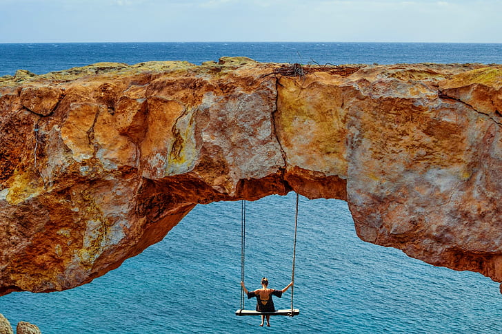 man swinging under cliff