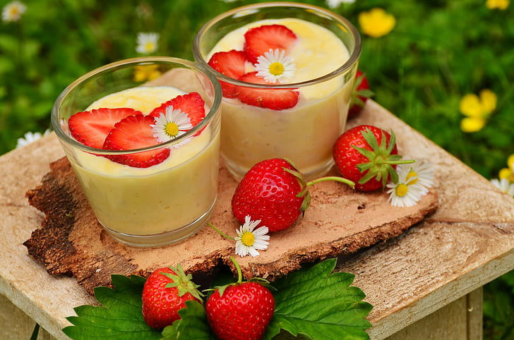 two clear glass filled with yellow beverage and three sliced of strawberries