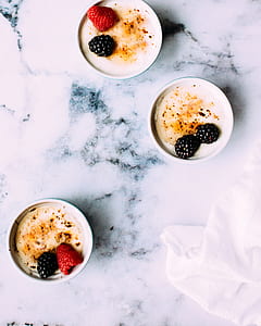 three white ceramic cup with white liquid and berries