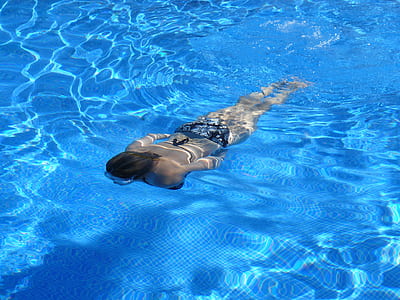 woman wearing bikini swimming on pool during daytime