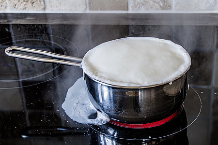 close photo of stainless steel cooking pot filled with white boiling liquid
