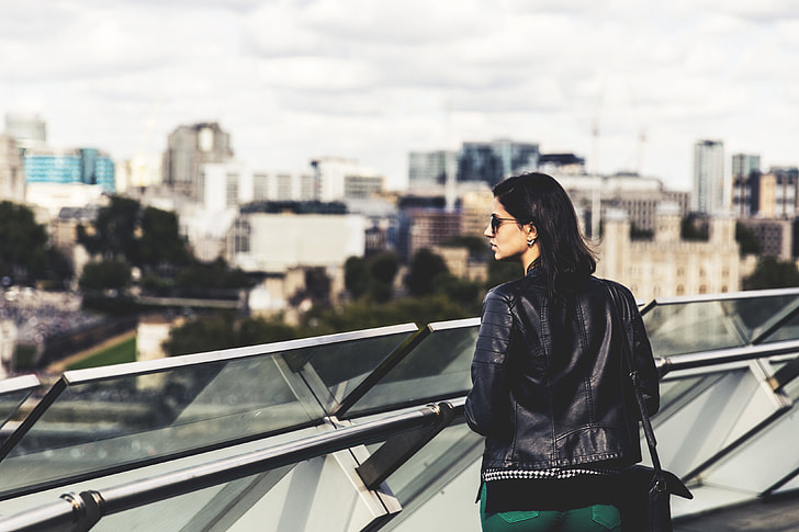 A woman wearing a leather jacket and sunglasses looks out across the City of London. Image captured with a Canon 6D