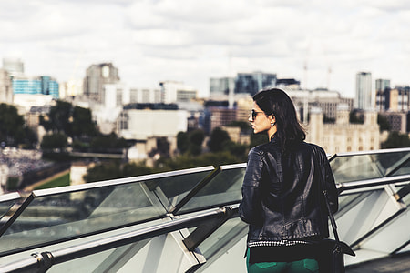 A woman wearing a leather jacket and sunglasses looks out across the City of London. Image captured with a Canon 6D