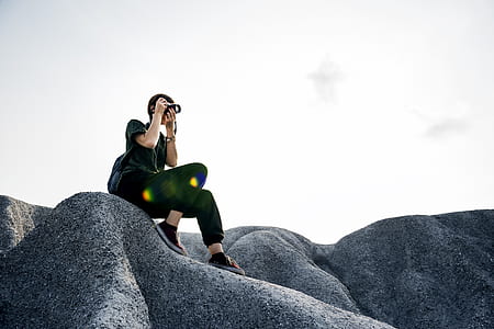 woman holding camera sitting on rock