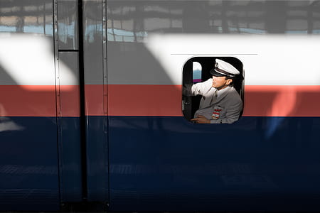 man wearing grey jacket inside white, red, and blue train