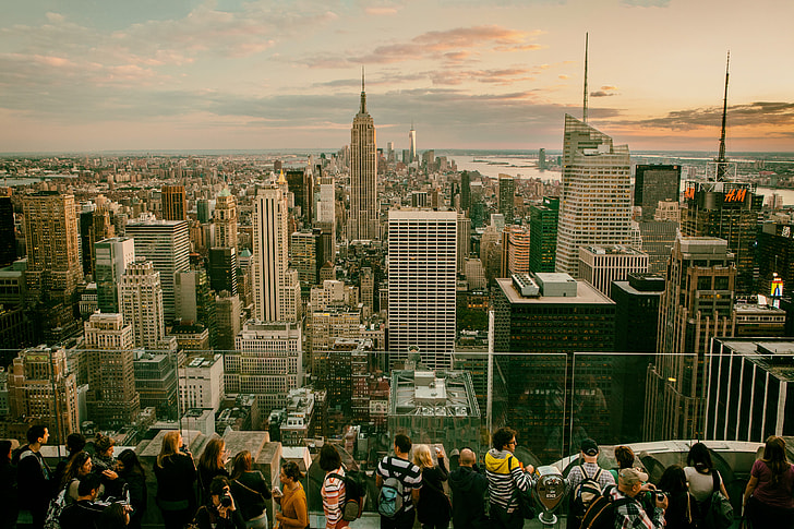 Tourists and sightseers gather on one of the Top Of The Rock observation decks at the Rockefeller Centre in Manhattan, New York City. The Empire State building can be seen in the background with views all the way down to Brooklyn and southern Manhattan