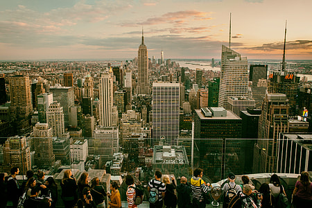 Tourists and sightseers gather on one of the Top Of The Rock observation decks at the Rockefeller Centre in Manhattan, New York City. The Empire State building can be seen in the background with views all the way down to Brooklyn and southern Manhattan