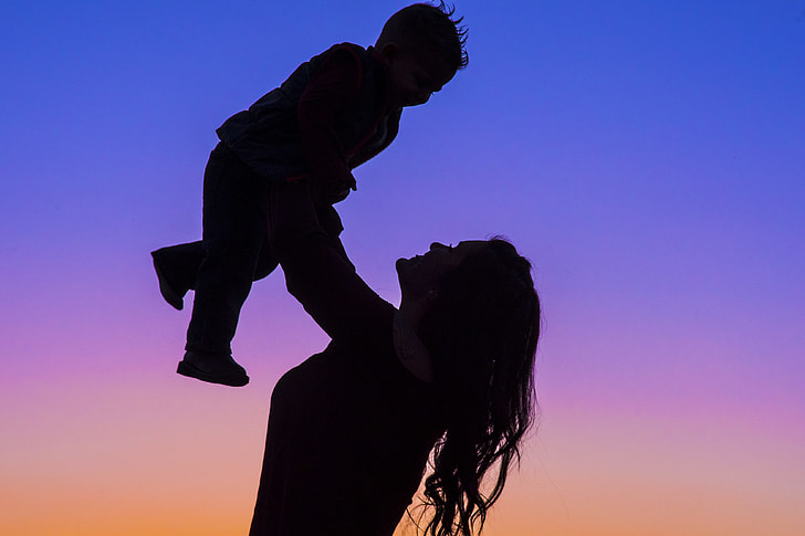 silhouette photo of woman carrying baby