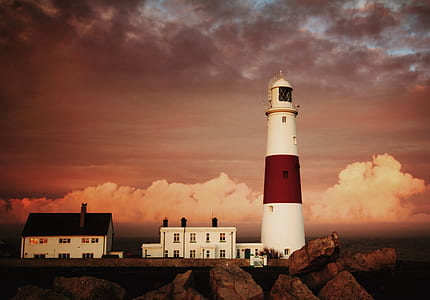 lighthouse on cliff with clouds in background