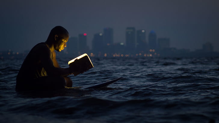 man holding a book on body of water