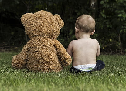toddler sitting together with brown bear plush toy