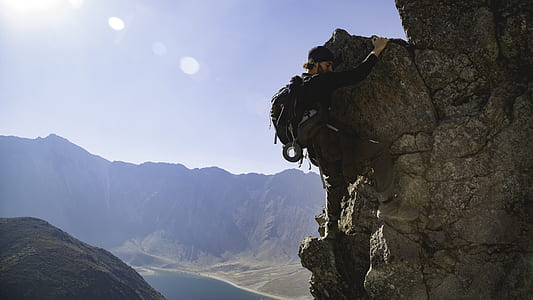 man wearing black long-sleeved shirt rock climbing during daytime landscape photography