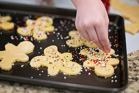 toddler sprinkling candies on cookie emulsion
