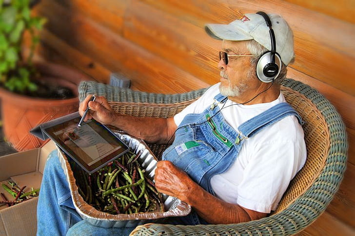 grandfather sitting on wicker brown armchair white using tablet computer