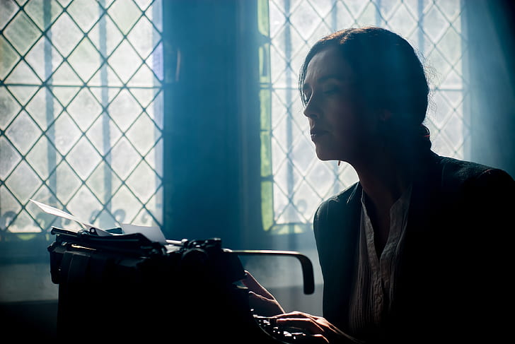woman in black top looking into black typewriter