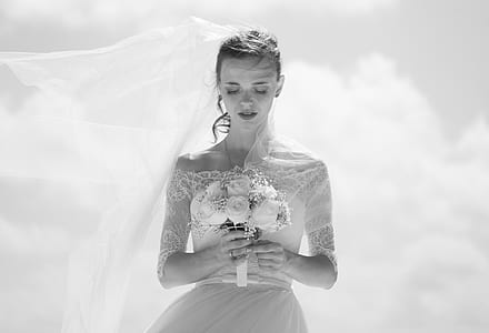 grayscale photo of woman wearing wedding gown holding bouquet