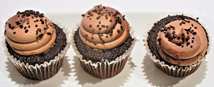 three chocolate cupcakes with icing and chocolate bits