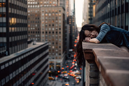 woman lying on brown building fence on the city photography during daytime