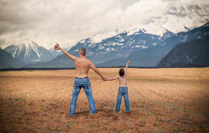 two topless man and child in front of ice-caped mountains