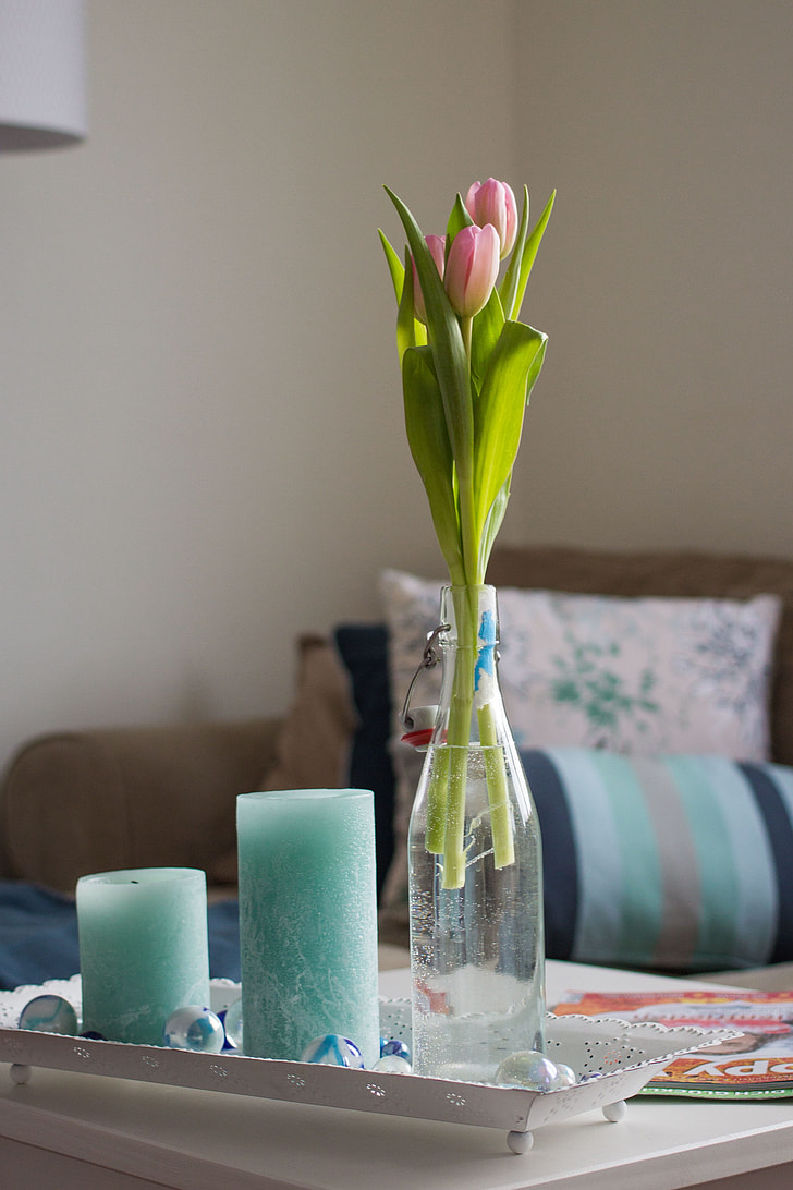 pink tulips with clear glass vase and two teal pillar candles