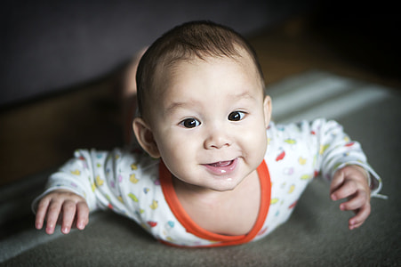 smiling baby wearing white and orange long-sleeved top