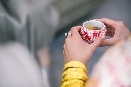 person holding white and red ceramic teacup