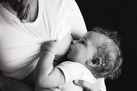 grayscale photography of woman breastfeeding baby