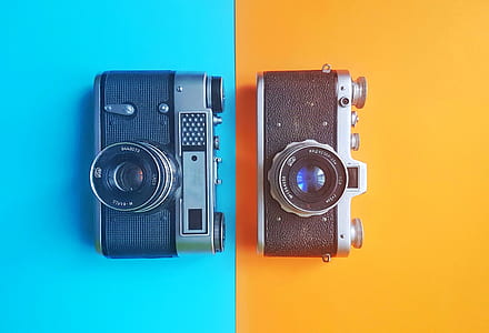 two black and grey mirrorless cameras on blue and yellow backgrounds
