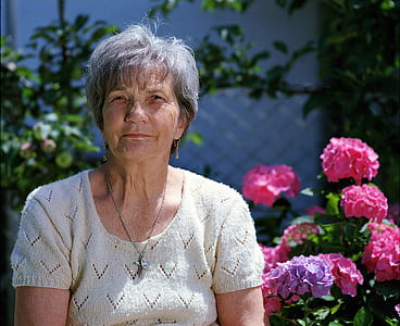 woman wearing white knitted blouse near pink flowers