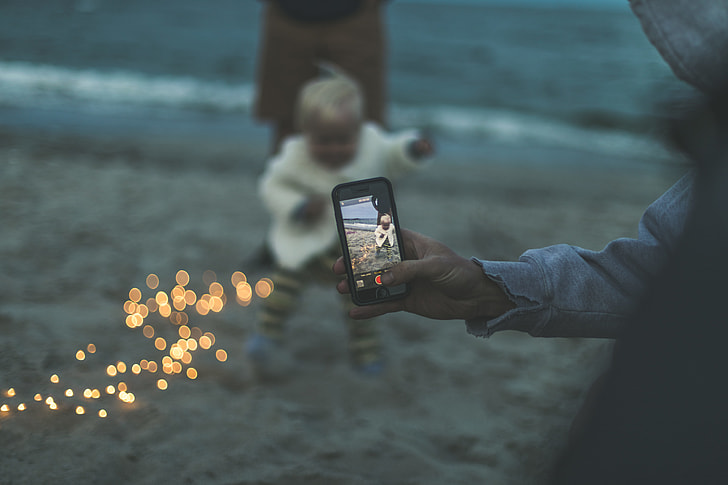 bokeh photography of person capturing baby
