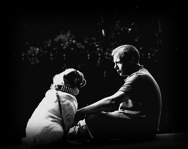 grayscaled photo of man holding dog