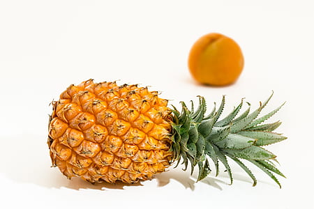 selective focus photography of ripe pineapple with orange fruit background