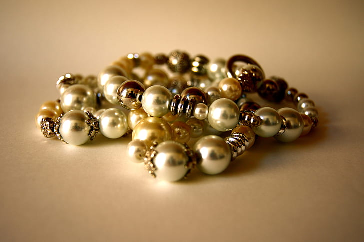beaded gold-colored bracelets on beige surface