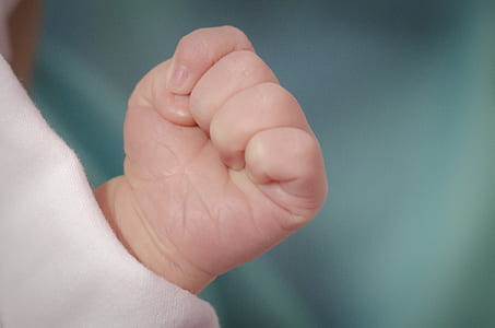 selective focus photography of infants hand forming a fist