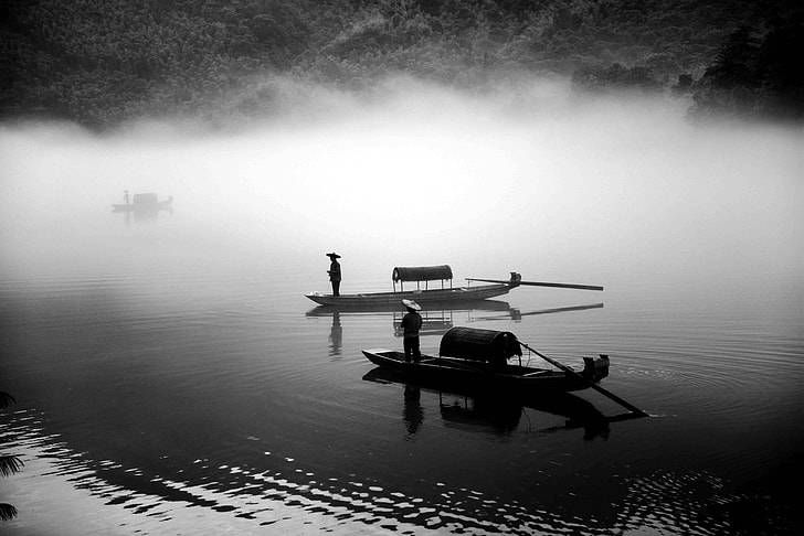 two man in boats on body of water grayscale photography