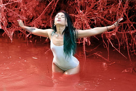 woman wearing white one-piece suit on red body of water