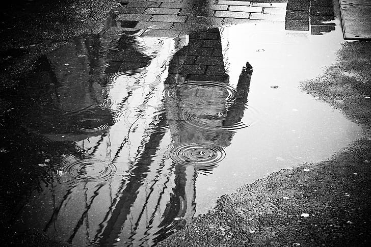 greyscale photography of puddle on grey concrete floor