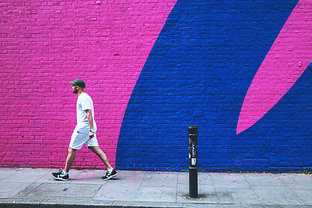 A man walks past a coloured brick wall in East London
