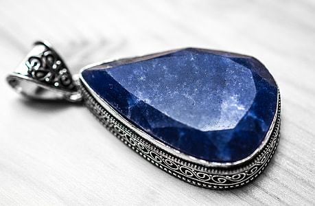 silver-colored pendant with blue gemstone