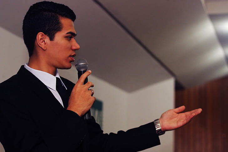 man wearing black suit jacket holding microphone