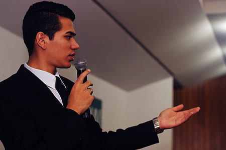 man wearing black suit jacket holding microphone