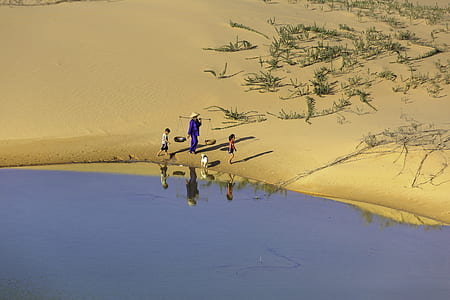 aerial photography of man wearing two kids beside river at daytime